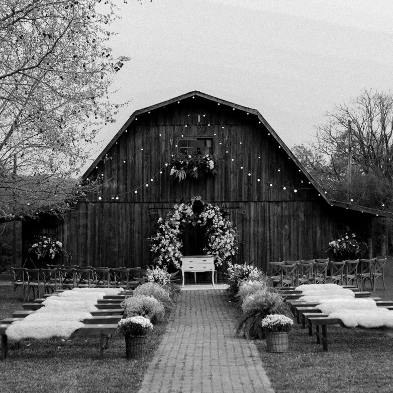 Rustic farm wedding venue with a charming artificial flower arch surrounded by natural greenery.