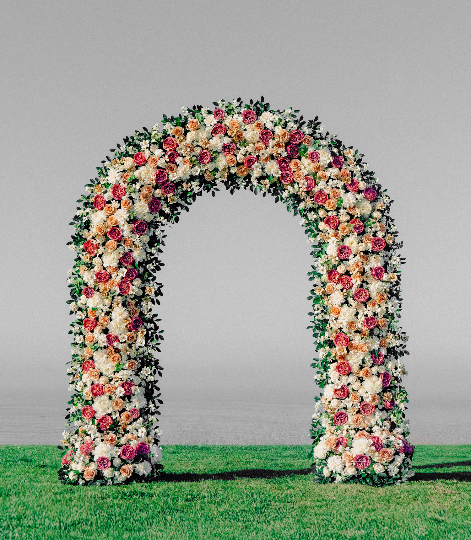 Boho wedding arch adorned with pink and mauve wildflowers, featuring airy florals and organic textures. A romantic, free-spirited design perfect for outdoor ceremonies and intimate garden weddings.