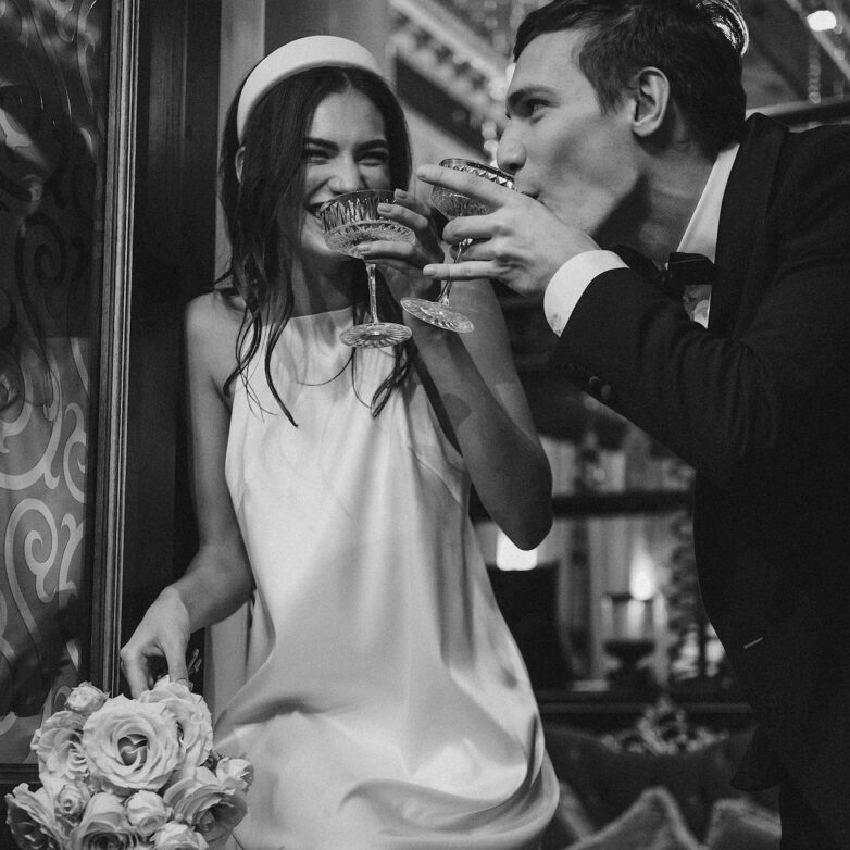 Happy couple laughing and enjoying drinks together, celebrating their special day.