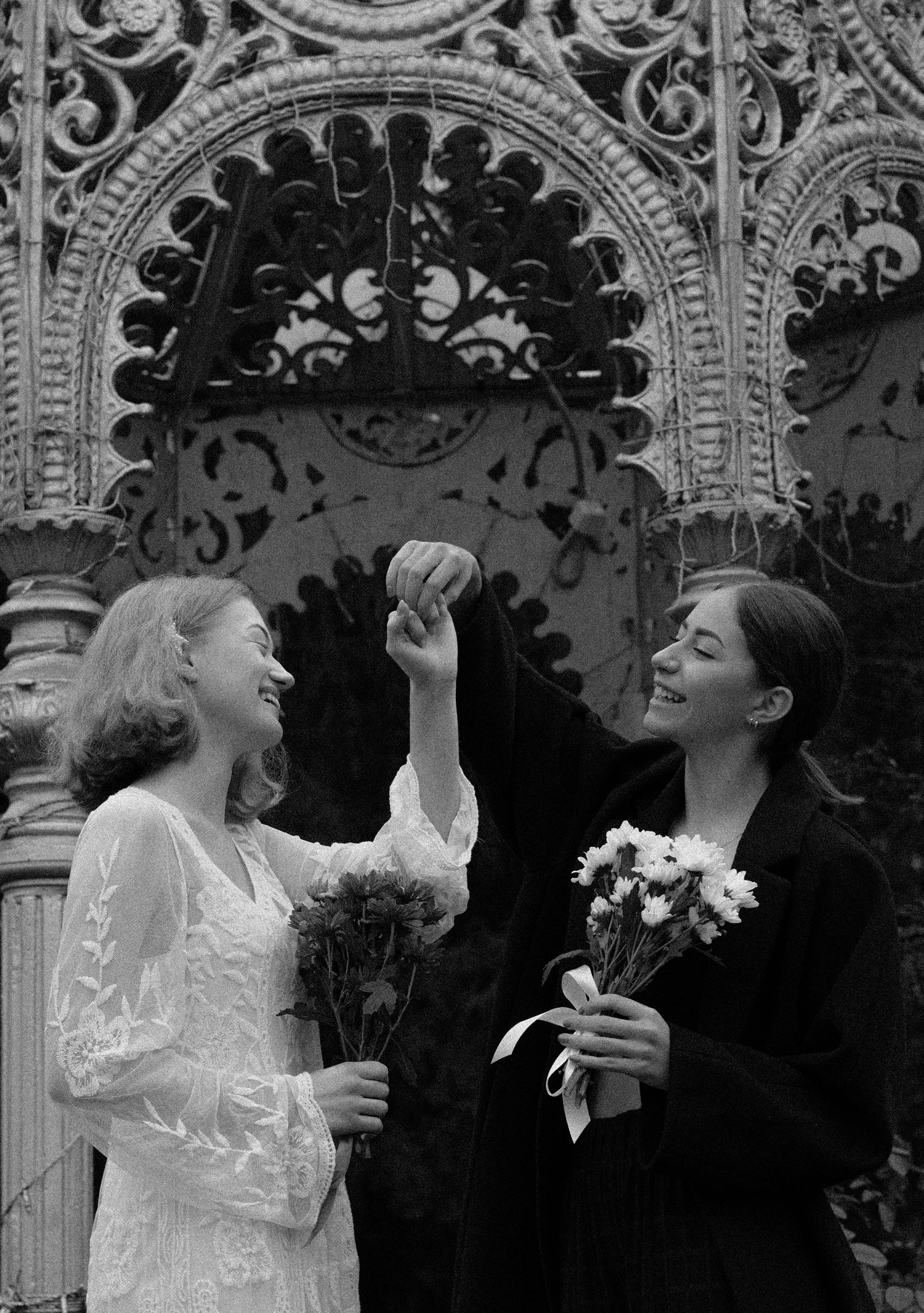 Two brides exchanging vows beneath a stunning artificial flower wedding arch, celebrating love in all its